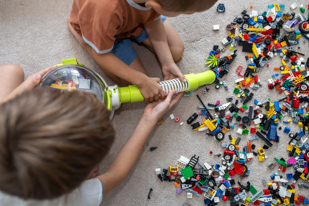 Two boys working together with Pick-Up Bricks to clean up their mess of LEGO spread across the floor